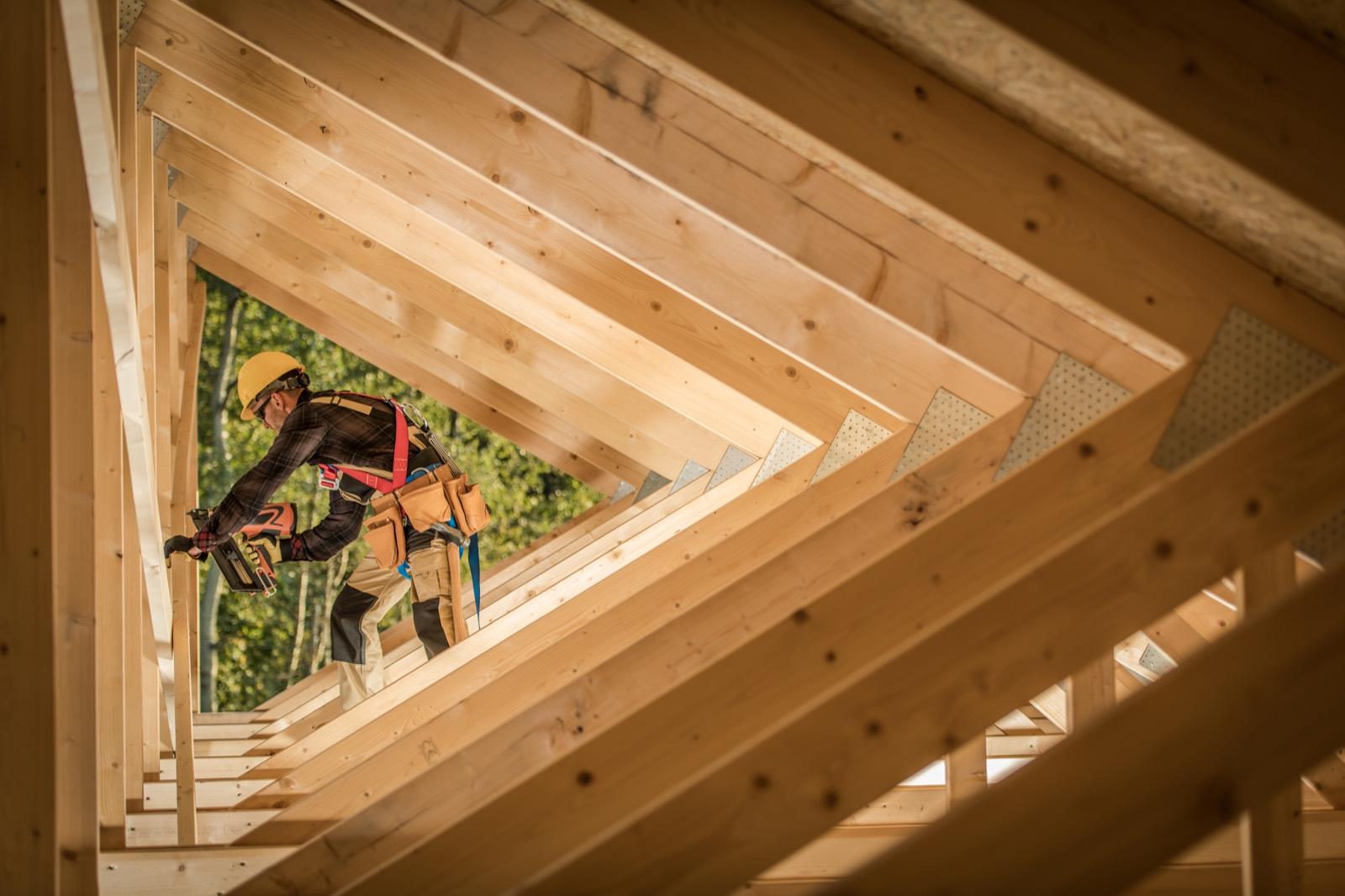 Operario montando la estructura de cubierta de madera de una vivienda