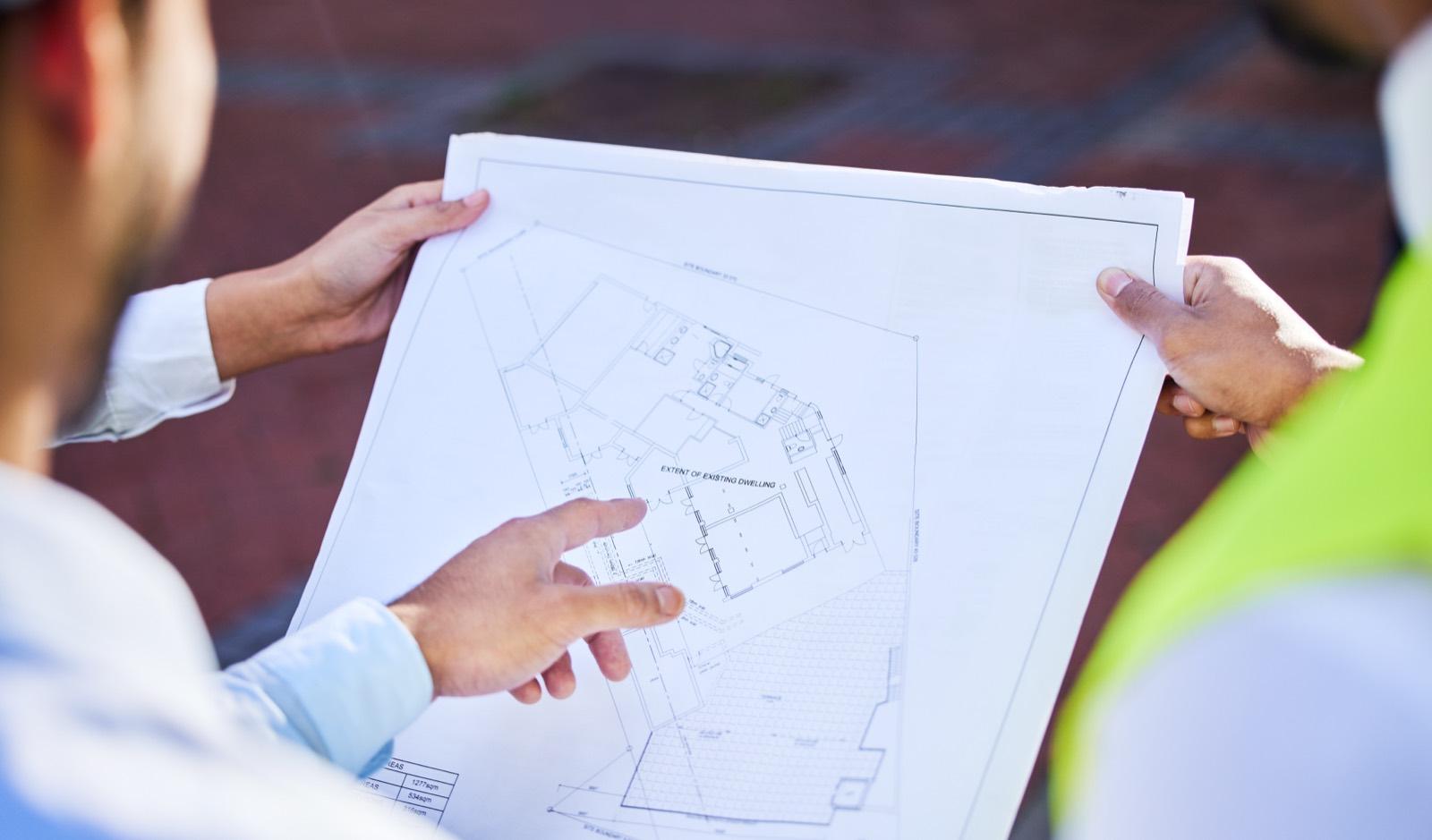 Dos técnicos revisando el plano de la parcela a pie de obra