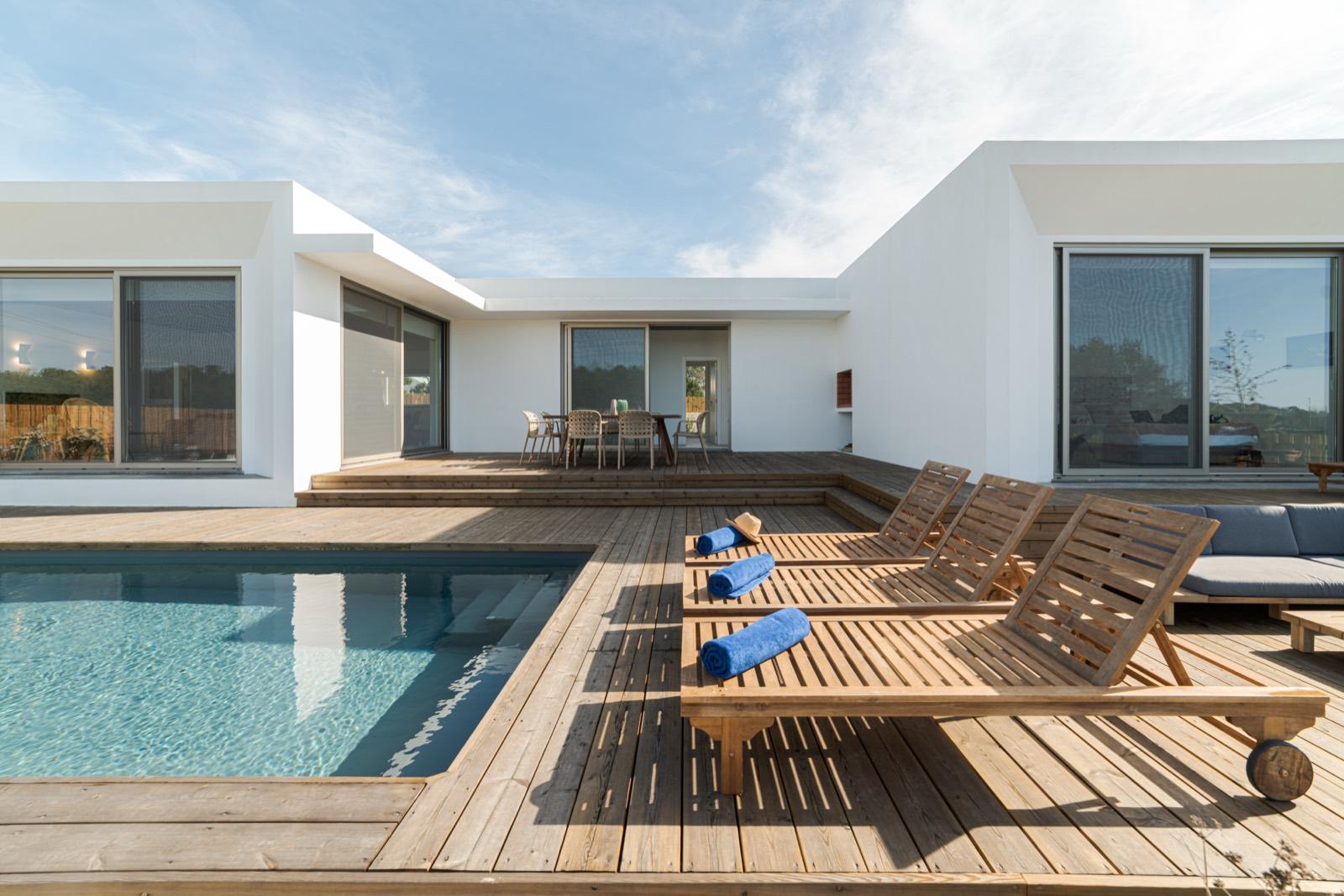 Vivienda de una planta con piscina y tumbonas sobre tarima