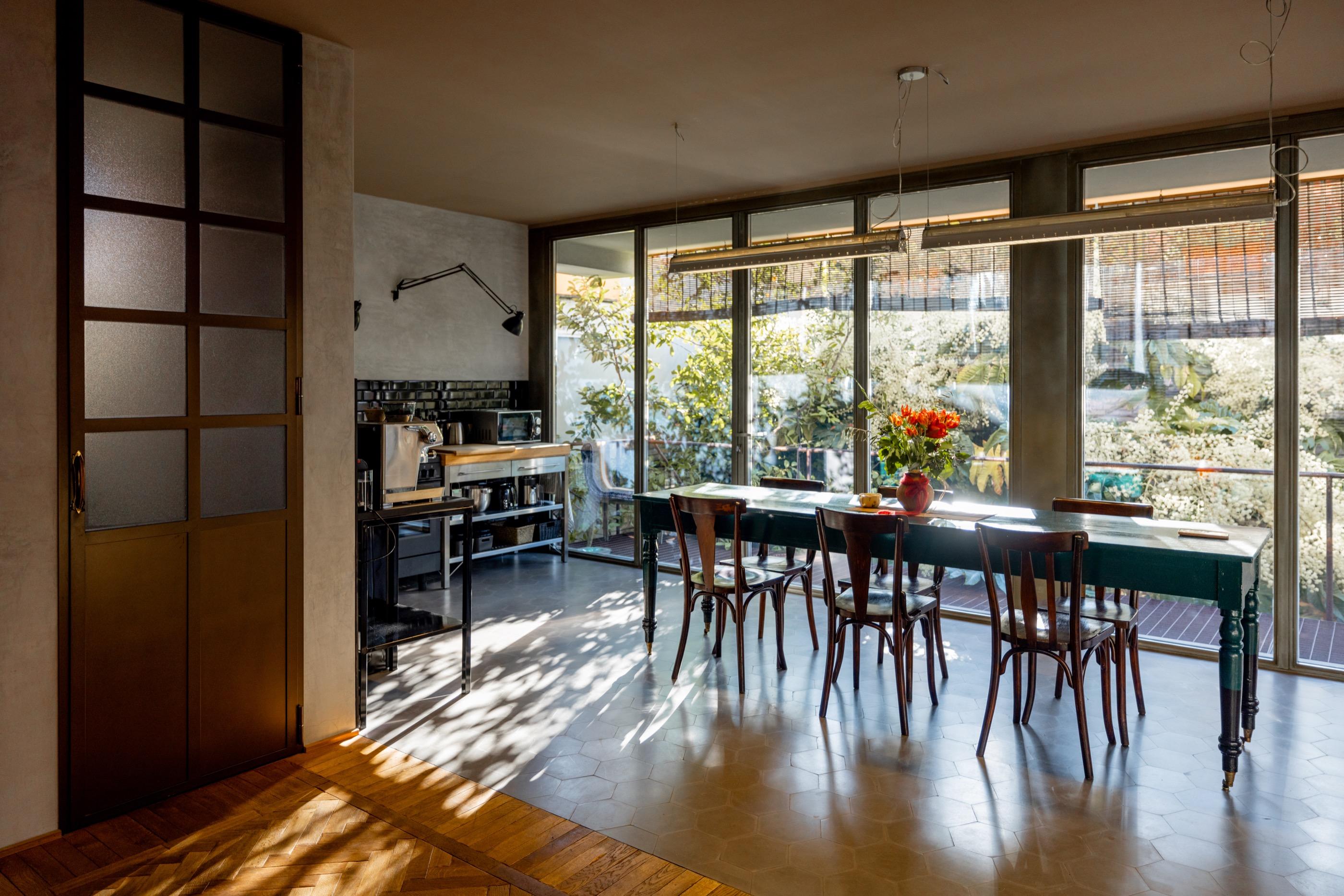 Comedor con mesa de madera y cristalera abierta al jardín