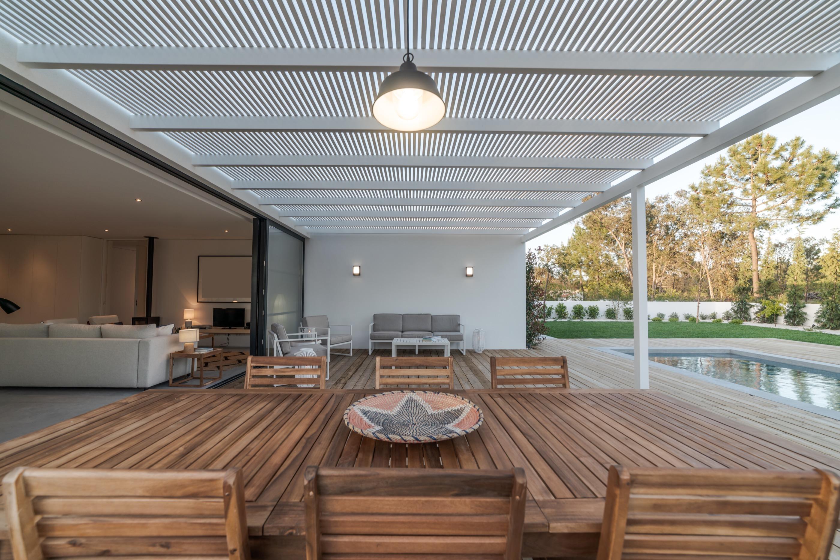 Pérgola de listones sobre un comedor exterior junto a la piscina