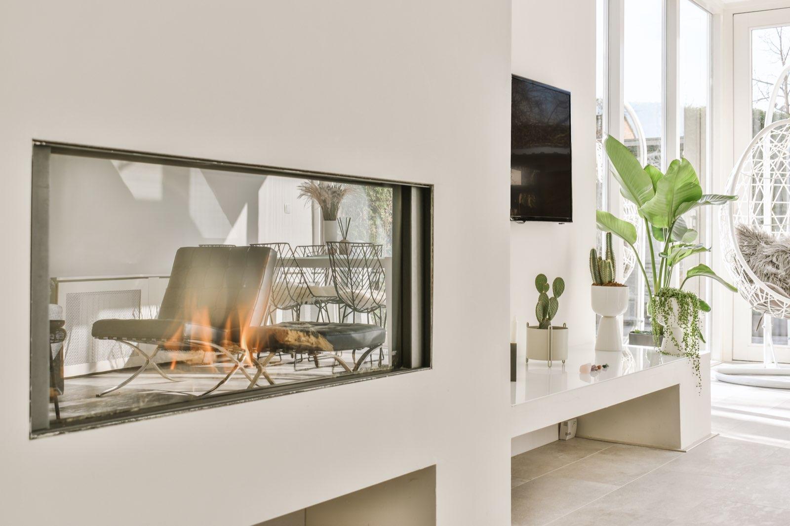 Salón terminado con chimenea de paso y ventanal al jardín