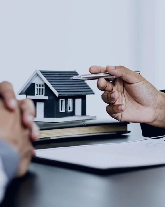 Firma de contrato de consulta con maqueta de vivienda sobre la mesa